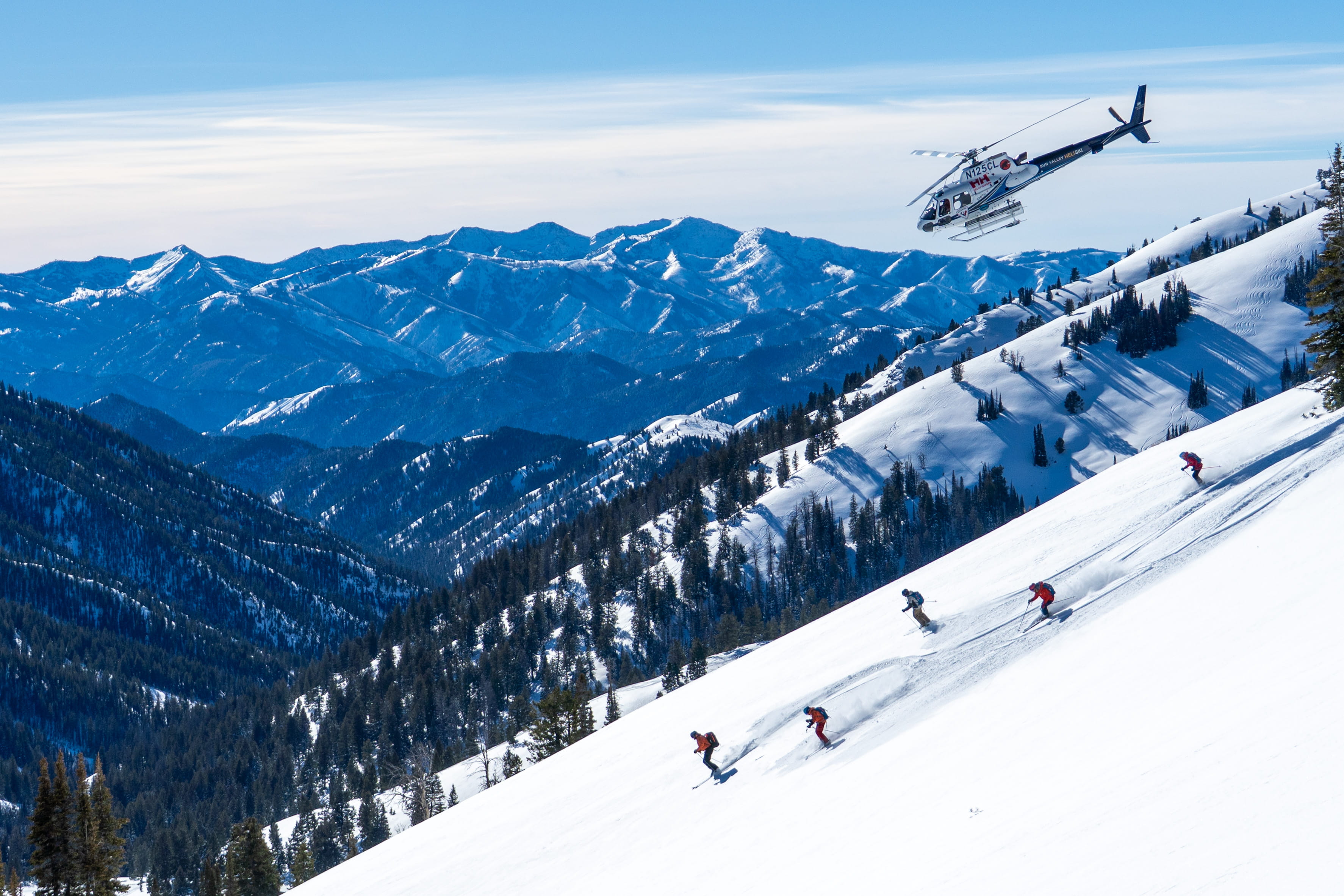 Skiers under a helicopter on a snowy mountain