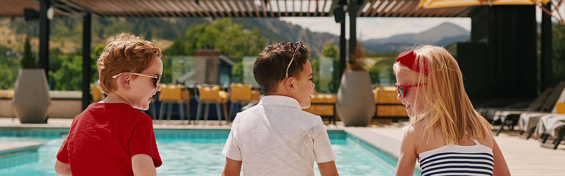 three kids sitting at the edge of boulder pool 